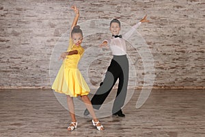 Beautifully dressed couple of kids dancing together in studio