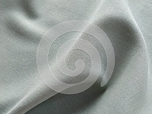 Beautifully folded light green fabric. Soft pleasant waves and flounces on textiles. Close-up. Drapery for curtains.