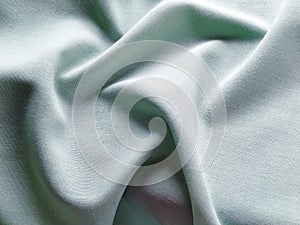 Beautifully folded light green fabric. Soft pleasant waves and flounces on textiles. Close-up. Drapery for curtains