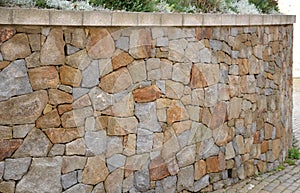 Beautifully folded retaining wall with a granite attic with small joints. brown beige yellow irregular gneiss stone holding a slop