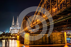 Beautifully illuminated Cologne Cathedral at night with golden reflections on the Rhine