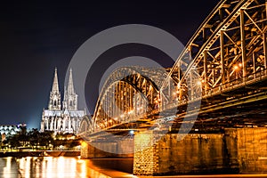 Beautifully illuminated Cologne Cathedral at night with golden reflections on the Rhine