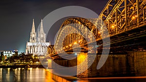 Beautifully illuminated Cologne Cathedral at night with golden reflections on the Rhine