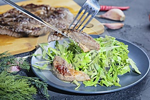Beautifully laid out freshly cooked steak on arugula. Beef medium rare