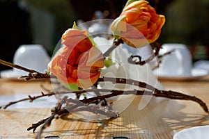 Beautifully laid wooden table with flowers and white coffee set.