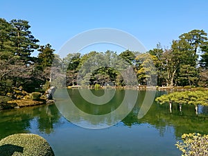 Beautifully landscaped park with a lake surrounded by trees. Reflection on the water. Pleasant. Calm.