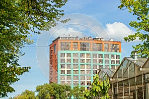 A beautifully modern building with large red green windows against a bright blue sky. Modern urban architecture, office high-rise