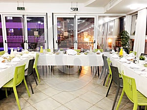 Beautifully organized event - served festive white tables ready for guests. Event in a restaurant.