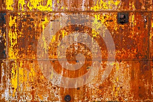 beautifully rusted rivetted sheet metal with leftovers of yellow paint texture and full-frame background