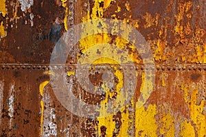 beautifully rusted rivetted sheet metal with leftovers of yellow paint texture and full-frame background