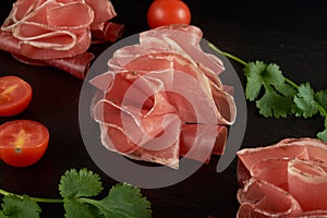 Beautifully served prosciutto or jamon on a black slate board.