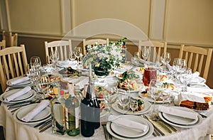 Beautifully set round tables at the restaurant. Delicious food at the wedding reception. White tablecloths and flowers decorations