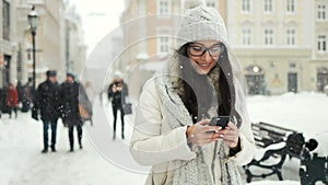 Beautifulwoman wearing winter coat and smiling happy while sending message with cellphone in the city