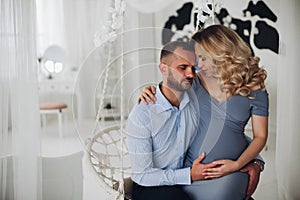 Beautiiful couple of pregnant woman and her husband embracing.