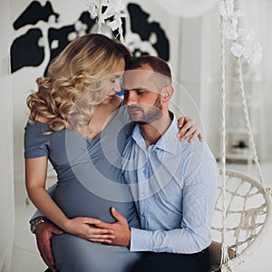 Beautiiful couple of pregnant woman and her husband embracing.