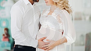 Beautiiful couple of pregnant woman and her husband embracing.