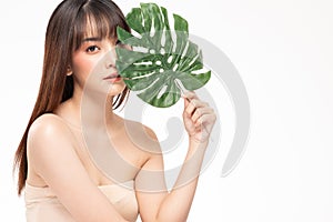 Beauty asian woman  brown hair looking smile in camera happiness and holds a large green tropical leaf in hands and covers a part