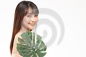 Beauty asian woman  brown hair looking smile in camera happiness and holds a large green tropical leaf in hands and covers a part