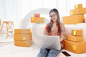 Beauty Asian woman using laptop for customer support in bedroom. Business and Technology concept. Delivery and Online shopping