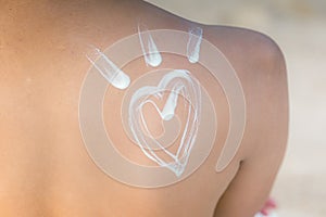 Beauty Attractive Asian young woman  smile with healthy skin applying sunscreen lotion Heart shape on her shoulder on the beach