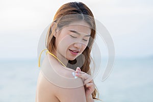 Beauty Attractive Asian young woman  smile with healthy skin applying sunscreen lotion on her shoulder on the beach