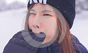 Beauty attractive woman with winter fashion clothing is making funny face in snow skii resort bitting her hand