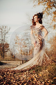 Beauty autumn woman in dress with leaves