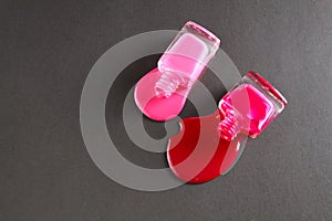 Beauty background two bottles of nail polish bottles red or burgundy pink spill poured on the table on a black background close-up