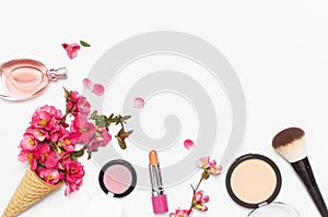 Beauty background. Waffle cone with pink spring flowers and different makeup cosmetic on light background. Face powder lipstick