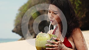 Beauty, baunty, travel, fashion concept.Beautiful pretty asian woman in hat and red dress drinking coconut on tropical