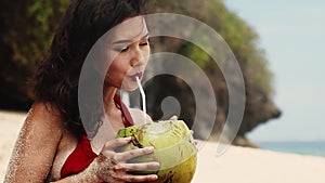 Beauty, baunty, travel, fashion concept.Beautiful pretty asian woman in hat and red dress drinking coconut on tropical