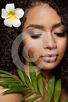 Beauty black skin woman fashion african ethnic female face portrait. Young girl model with afro and tropical leaves in hands