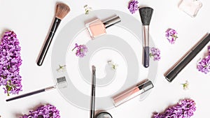 Beauty blog background. Purple spring bouquet of lilac branches, cosmetic accessories. Flat lay, top view. Copy space