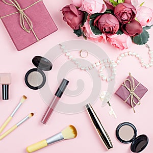 Beauty blog concept flat lay. Fashion accessories, flowers, cosmetics, jewelry on pink background.