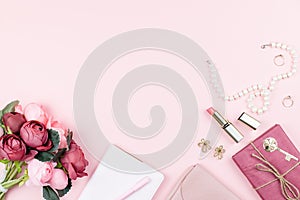 Beauty blog concept flat lay. Fashion accessories, flowers, cosmetics, jewelry on pink background, copyspace.