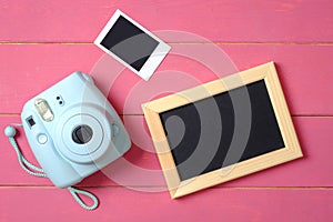 Beauty blogger accessories. Modern polaroid photo camera, picture frame and image on pink wooden background. Top view, flat lay