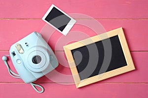 Beauty blogger accessories. Modern polaroid photo camera, picture frame and image on pink wooden background. Top view, flat lay