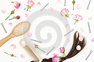 Beauty blogger composition with comb for hair styling, barrette and pink flowers on white. Flat lay, top view