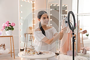 Beauty blogger preparing for video recording in room at home. Using ring lamp and smartphone