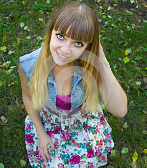 Beauty blonde teen girl with big eyes sitting on grass