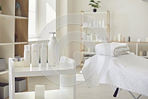 Spa room or beauty salon with set of organic skincare products and empty bed with fresh towels