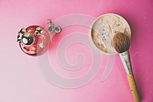 Beauty box, powder with a brown brush from nap for makeup, pink perfume and earrings on a background. Flat lay. Top view