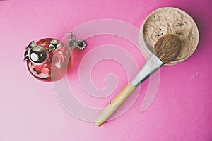 Beauty box, powder with a brown brush from nap for makeup, pink perfume and earrings on a background. Flat lay. Top view