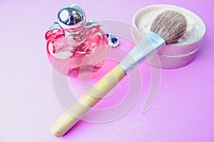 Beauty box, powder with a brown brush from nap for makeup, pink perfume and earrings on a background. Flat lay. Top view