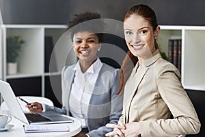 Beauty and brains - they have both. two businesswomen seated at a table with a laptop.