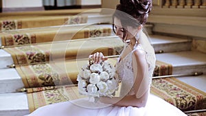 Beauty bride in bridal gown with bouquet and lace veil indoors