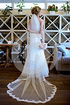 Beauty bride in bridal gown with bouquet and lace veil indoors