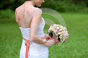 Beauty bride in bridal gown with bouquet and lace veil in the nature