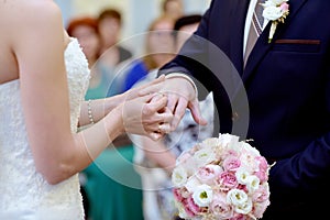 Beauty bride and handsome groom are wearing rings each other