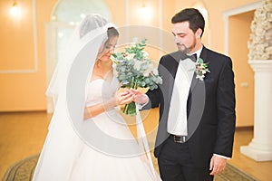 Beauty bride and handsome groom are wearing rings each other. Wedding couple on the marriage ceremony.